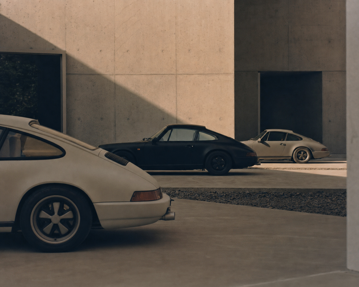 Tre klassiska Porsche 911 i en avskalad betongmiljö